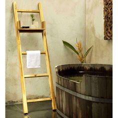 a wooden ladder leaning up against a wall next to a bathtub with a towel on it