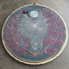 an embroidery project is shown on the ground with a ladybug sitting on it