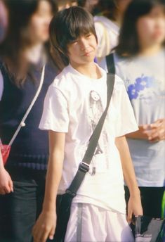 a young boy is standing in front of a group of people with his back to the camera