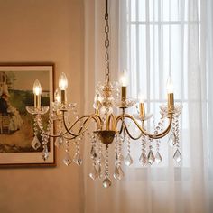 a chandelier hanging from the side of a window in a room with white curtains