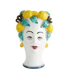 a white ceramic head with yellow and green leaves on it's hair, wearing earrings