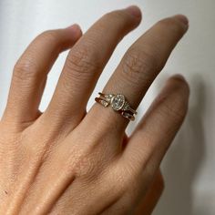 a woman's hand with a diamond ring on top of her finger and the other hand holding an engagement ring