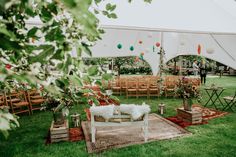 an outdoor wedding setup with chairs, tables and rugs on the grass in front of a tent