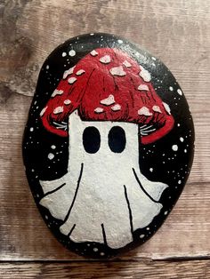 a painted rock with a red mushroom on it's head and hearts in the background