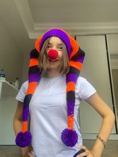 a woman wearing a knitted clown hat with pom - poms on her head