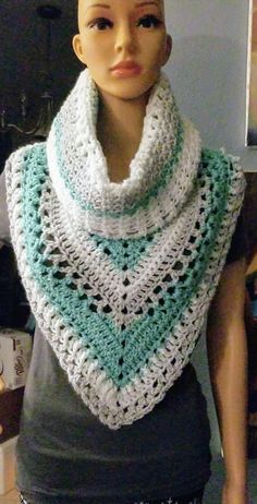 a mannequin wearing a crocheted shawl in white and aqua blue