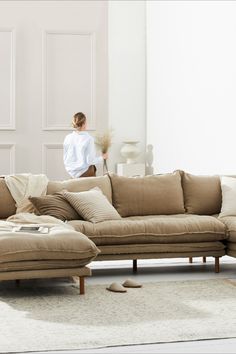 a woman is standing in the background behind a couch with pillows on top of it