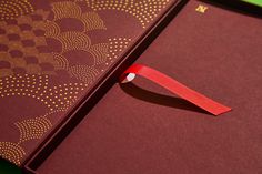 an open book with a red ribbon on the front and back cover, sitting on a green surface