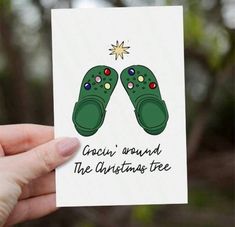 someone holding up a christmas card with two green shoes on it