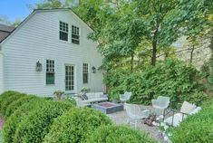 a white house sitting next to a lush green forest