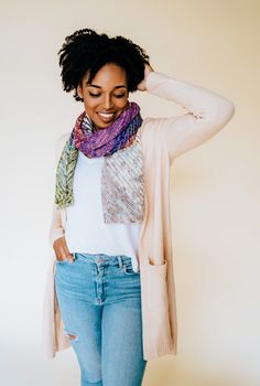 a woman with her hands on her head, wearing jeans and a cardigan sweater