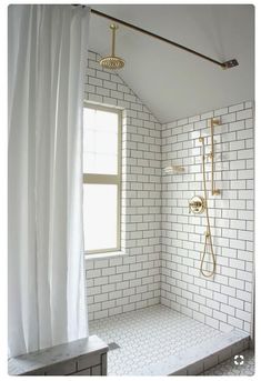 a white tiled bathroom with a window and shower head in the corner on the wall