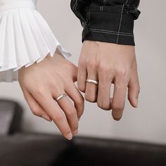 two people holding hands with wedding rings on their fingers and one wearing a dress shirt