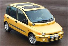 a small yellow car is parked in a parking lot