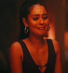 a woman with large hoop earrings on her face looking at the camera while sitting down