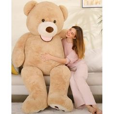 a woman hugging a giant teddy bear on the floor in front of a white couch