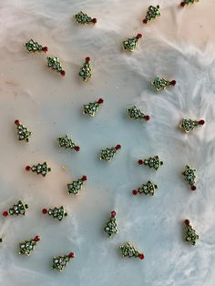 there are many small pieces of jewelry on the white tablecloth with red and green beads