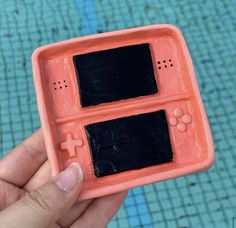 a hand holding an orange and black nintendo wii game controller case in front of a swimming pool