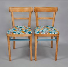 two wooden chairs with colorful upholstered seats on each one and the other side