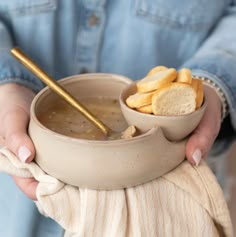 a person holding a bowl of soup and some bread