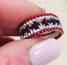 a person is holding a ring with red and white beads on the inside of it