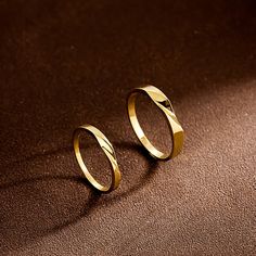 two gold rings sitting on top of a brown surface