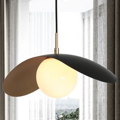 a modern light hanging over a table in front of a window with sheer drapes