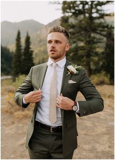 a man in a suit and tie is posing for the camera with his hands on his hips