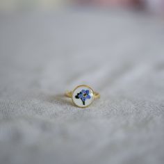 A simple ring to add a touch of nature to any outfit! This ring is handmade using pressed Forget Me Not flowers preserved in resin, and the ring is Sterling Silver. The Forget Me Not flower has so many meanings, and makes a great gift or stocking filler to someone you care about. It's best to not wear this ring in the shower/bath etc, and every time you wash your hands, as it's handmade, but every once in a while should be fine. Dainty Flower Ring With Birthstone, Dainty Flower Ring With Round Band For Gift, Dainty Flower Ring With Round Band As Gift, Dainty Round Flower Promise Ring, Minimalist Flower Jewelry For Promise, Dainty Flower Ring With Round Band, Delicate Birthstone Flower Ring, Birth Flower Open Ring For Promise, Yellow Gold Round Flower Ring Gift