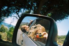 a woman taking a selfie in the side view mirror of a car with her sunglasses on