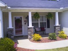 a house with columns and landscaping in front of the door, on a sunny day