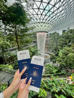 two people holding up their passport in front of a glass dome at the gardens by the bay