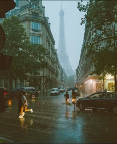 people crossing the street in front of the eiffel tower on a rainy day