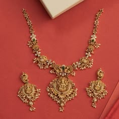 Description: This alluring necklace set from Tarinika features handcrafted designs decorated with temple elements surrounded with peacocks and flower motifs made of CZ stones and pearls on an antique gold base. Style this intricate temple set with any ethnic outfit. Details & Specifications:Materials used: Brass Alloy with Antique platingWeight - Necklace: 67 gms, Earrings: 29 gmsLength - Necklace: 19.5 cms, Earrings: 7.5 cmsMake it customWant to make it a custom necklace? Sure! Reach out to us Gold Necklace Set With Pearls, Antique Simple Necklace, Antique Gold Set Designs, Intricate Gold Necklace, Gold Necklace Designs For Bride, Gold Necklace With Earrings Set, Necleses Jewelry Gold Indian Latest, Tarinika Jewellery, New Model Necklace Designs Gold