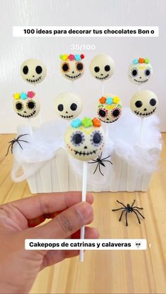 a hand holding a cake pops with skulls on them