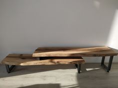 two wooden benches sitting next to each other on top of a hard wood floor in front of a white wall