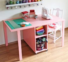 a pink table with sewing supplies on it in front of a white wall and wooden floor