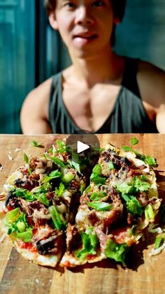 a person sitting at a table with a pizza in front of them and the man behind it