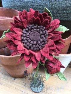 a large red flower sitting on top of a wooden table next to potted plants