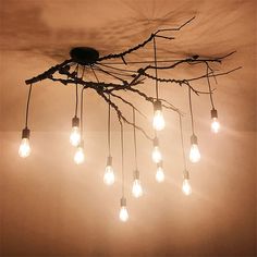 a chandelier made out of branches with light bulbs hanging from the top and bottom