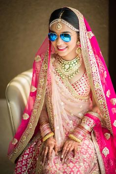 a woman in a pink and gold bridal outfit with her hands out to the side