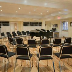 a room filled with lots of chairs and a black piano in the middle of it