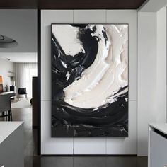 an abstract black and white painting hangs on the wall in this modern living room area