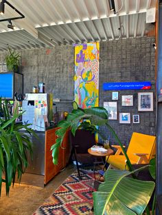 a living room filled with lots of plants next to a wall covered in pictures and paintings