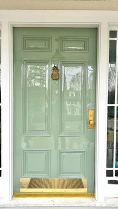 a green front door with two windows and a bench