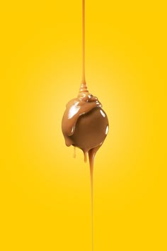 a chocolate covered donut being drizzled with caramel syrup on a yellow background