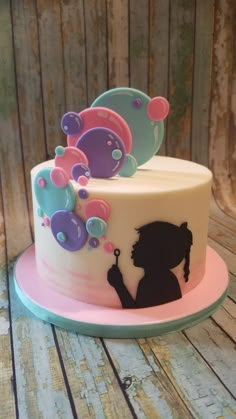 two tiered cake decorated with silhouettes of girls blowing bubbles on it's sides