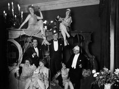 a group of people sitting around each other in front of a fire place with candles