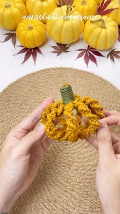 someone is holding a crochet pumpkin decoration