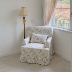 a chair sitting in front of a window next to a lamp